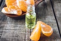 A bottle of mandarin essential oil and slices of ripe yellow mandarin lie on a wooden table Royalty Free Stock Photo