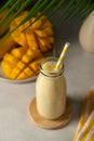 Bottle of mango, banana and yoghurt smoothie with a straw.