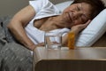 Bottle of medicine and water with senior woman sleeping in backg Royalty Free Stock Photo