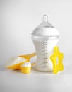 Bottle of milk for baby and measuring scoops with powder on light background