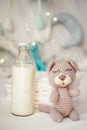 Bottle of milk with bear toy and stack of diapers on bed