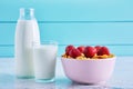 Bottle of milk, bowl of cereal corn flakes with strawberry topping and a glass full of milk on a wooden table Royalty Free Stock Photo