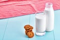 Bottle of milk, a glass full of milk, chocolate chip cookies and a tablecloth on blue wooden table. Royalty Free Stock Photo