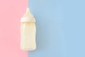 Bottle of milk for newborn baby over pink and blue pastel colors background. Maternity and baby care concept. Girl or boy. Top vie Royalty Free Stock Photo