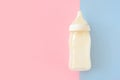 Bottle of milk for newborn baby over pink and blue pastel colors background. Maternity and baby care concept. Top view. Royalty Free Stock Photo