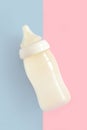 Bottle of milk for newborn baby over pink and blue pastel colors background. Maternity and baby care concept. Top view. Royalty Free Stock Photo