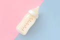 Bottle of milk for newborn baby over pink and blue pastel colors background. Maternity and baby care concept. Top view. Royalty Free Stock Photo