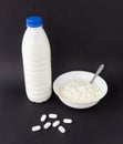 A bottle of milk and a plate of cottage cheese on a black background near lie pills of antibiotics, close-up, pills Royalty Free Stock Photo