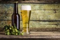 Bottle and mug full of beer with bunch of hops on wood background Royalty Free Stock Photo