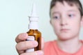 A bottle of nasal spray in a hand of a boy close up, allergy, viral and bacterial rhinitis and sinusitis treatment