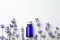 Bottle with natural essential oil and lavender flowers on white wooden background. Space for text Royalty Free Stock Photo