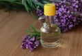 Bottle of natural essential oil and lavender flowers on wooden table, closeup Royalty Free Stock Photo