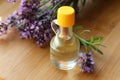 Bottle of natural essential oil and lavender flowers on wooden table, closeup Royalty Free Stock Photo