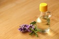 Bottle of natural essential oil and lavender flowers on wooden table, closeup. Space for text Royalty Free Stock Photo