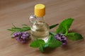 Bottle of natural essential oil, mint leaves and lavender flowers on wooden table, closeup Royalty Free Stock Photo