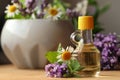 Bottle of natural lavender essential oil near mortar with flowers on wooden table, closeup. Space for text Royalty Free Stock Photo