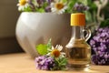 Bottle of natural lavender essential oil near mortar with flowers on wooden table, closeup. Space for text Royalty Free Stock Photo