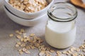 Bottle of oat milk and oat grains in bowl on table Royalty Free Stock Photo