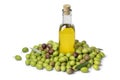 Bottle olive oil surrounded by fresh raw green olives on white background