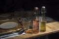 A bottle of olive oil and vinegar is about a napkin and a fork with a knife on a set table.