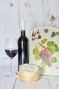 Bottle and one glass of red wine and camembert cheese on a white wood background Royalty Free Stock Photo