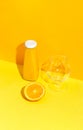 Bottle with orange juice and fresh orange and empty glass on the table.