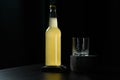 A bottle of orange juice, lemonade, alcoholic beverage and an empty glass standing on black wooden table Royalty Free Stock Photo