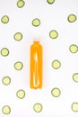 Bottle of orange smoothie on white background with cucumber pattern. Top view. Vertical. Detox summer drink. Healthy fresh juice Royalty Free Stock Photo