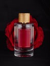 a bottle of perfume against a large red flower against a dark background Royalty Free Stock Photo