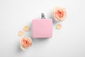 Bottle of perfume, beautiful roses and petals on white background, flat lay