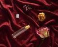 A bottle of perfume and buds of dried roses on a red silk background. Romantic look. Top view Royalty Free Stock Photo