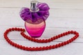 Bottle of perfume and red beads necklace on white wooden background Royalty Free Stock Photo