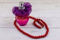 Bottle of perfume and red beads necklace on white wooden background Royalty Free Stock Photo