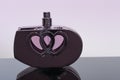 Bottle of perfume in the shape of a heart on black acrylic shee