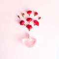 A bottle of perfume splashing red roses. Minimal concept on a light pink background Royalty Free Stock Photo