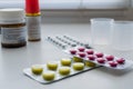 Bottle pills, measuring cup and medicine capsule on table