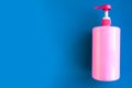 Bottle with pink dishwashing liquid on blue background. Minimal concept. Royalty Free Stock Photo
