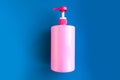 Bottle with pink dishwashing liquid on dark blue background. Royalty Free Stock Photo