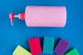 Bottle with pink dishwashing liquid and multicolor sponges on blue background. Royalty Free Stock Photo
