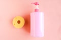 Bottle with pink dishwashing liquid and sponge on pink background. Royalty Free Stock Photo