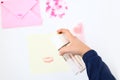 A bottle of pink perfume in hand puffs on a note with lipstick print. Making postcard in envelope for Valentine`s Day. Envelope,