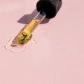Bottle pipette dropper and Liquid yellow-orange retinol or vitamin c gel or serum on a pink background