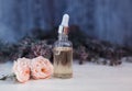 bottle with pipette and lavender and rose oil stands on a wooden table next to delicate lilac and pink fragrant flowers Royalty Free Stock Photo