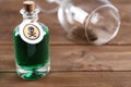 Bottle of poison and partially emptied glass on wooden table
