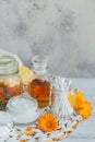 A bottle of pot marigold tincture or infusion, ointment, cream or balm with fresh and dry calendula flowers and cotton pad and Royalty Free Stock Photo