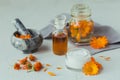 A bottle of pot marigold tincture or infusion, ointment, cream or balm with fresh and dry Calendula flowers on light Royalty Free Stock Photo