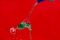 Bottle pouring green liquid into an overflowing glass cup Royalty Free Stock Photo