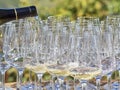 A bottle pouring wine into some glasses with the Langhe countryside in the background Royalty Free Stock Photo