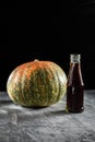 In a bottle, pumpkin oil is next to the pumpkin. Vertical orientation