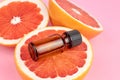 Bottle with pure grapefruit essential oil on grapefruit halves. Aromatherapy treatment concept.